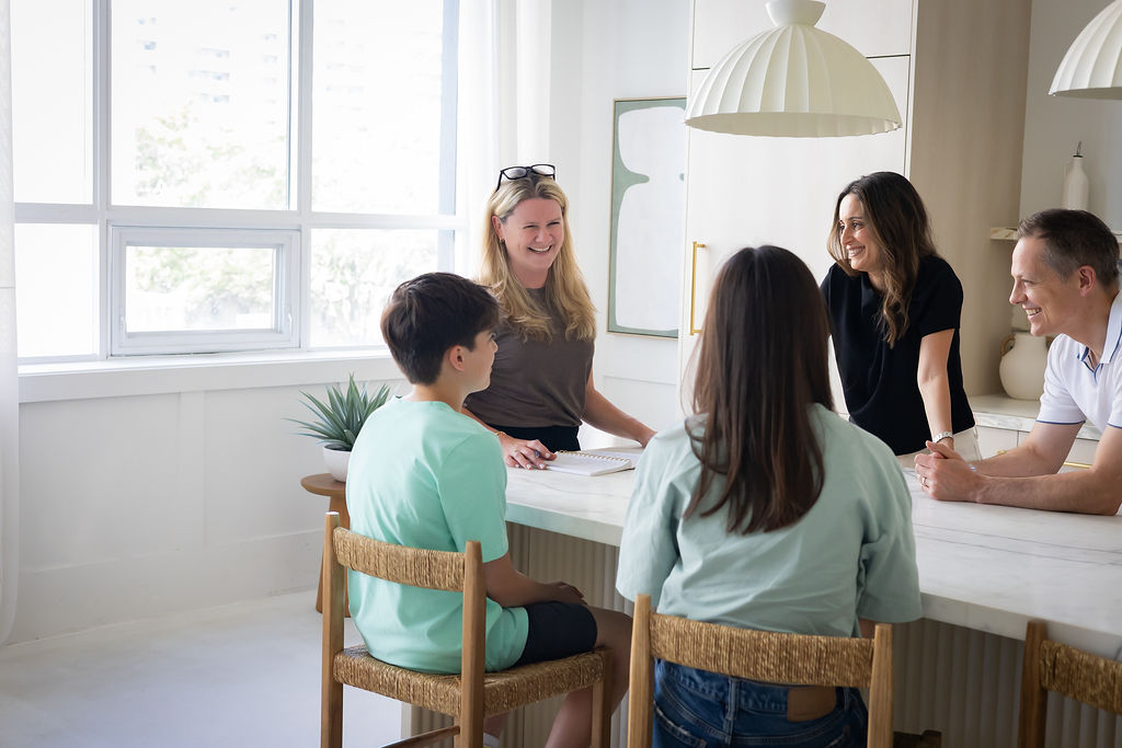 Sarah with a family gathered around their kitchen counter